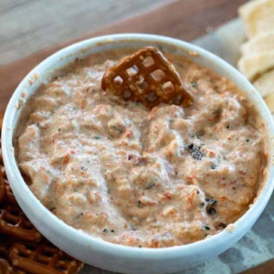 bowl of roasted vegetable dip with pretzles and sliced bread