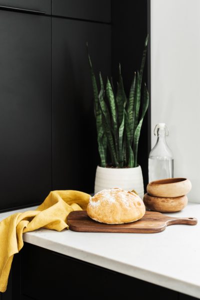 fresh baked bread, a yellow towel, plant, and bowls on a kitchen counter