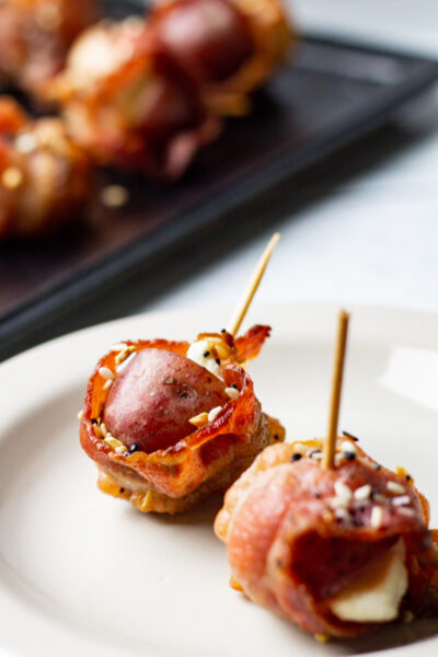 two everything bagel bacon wrapped potato appetizers on a white plate