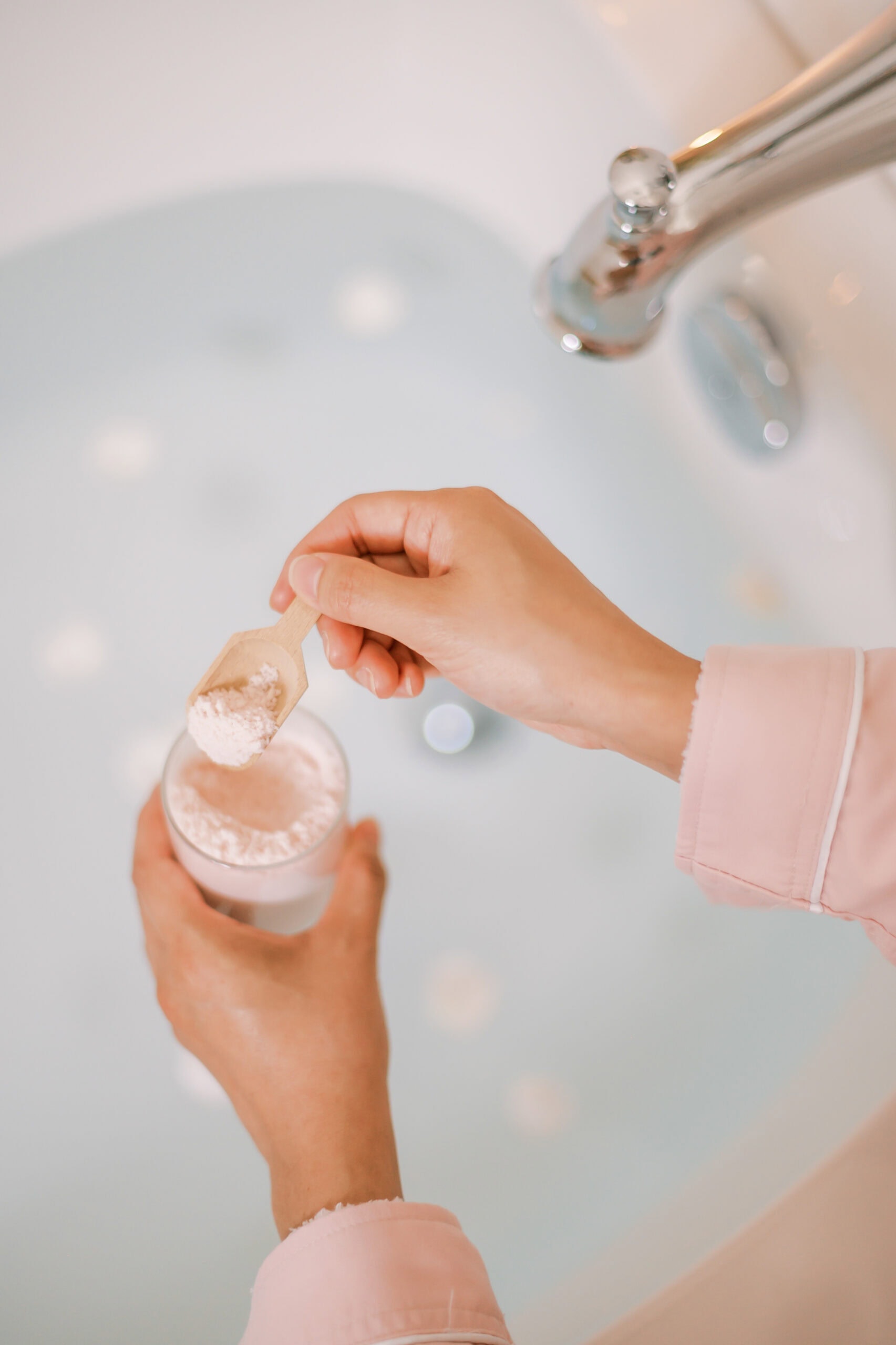 non descript hands putting bath salts in a tub for a cozy home spa day