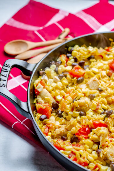 Staub pan with southwest chicken and rice on a red and white checkered placemat