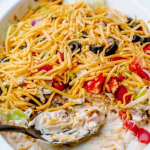 half eaten dish of supreme taco dip with ground beef, cheese, peppers, and olives