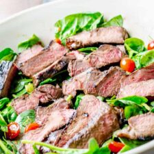 close up of rosemary grilled steak salad with spinach and grape tomatoes