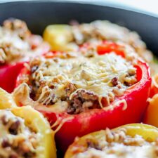 close up of red and yellow ground beef stuffed bell peppers in a cast iron pan