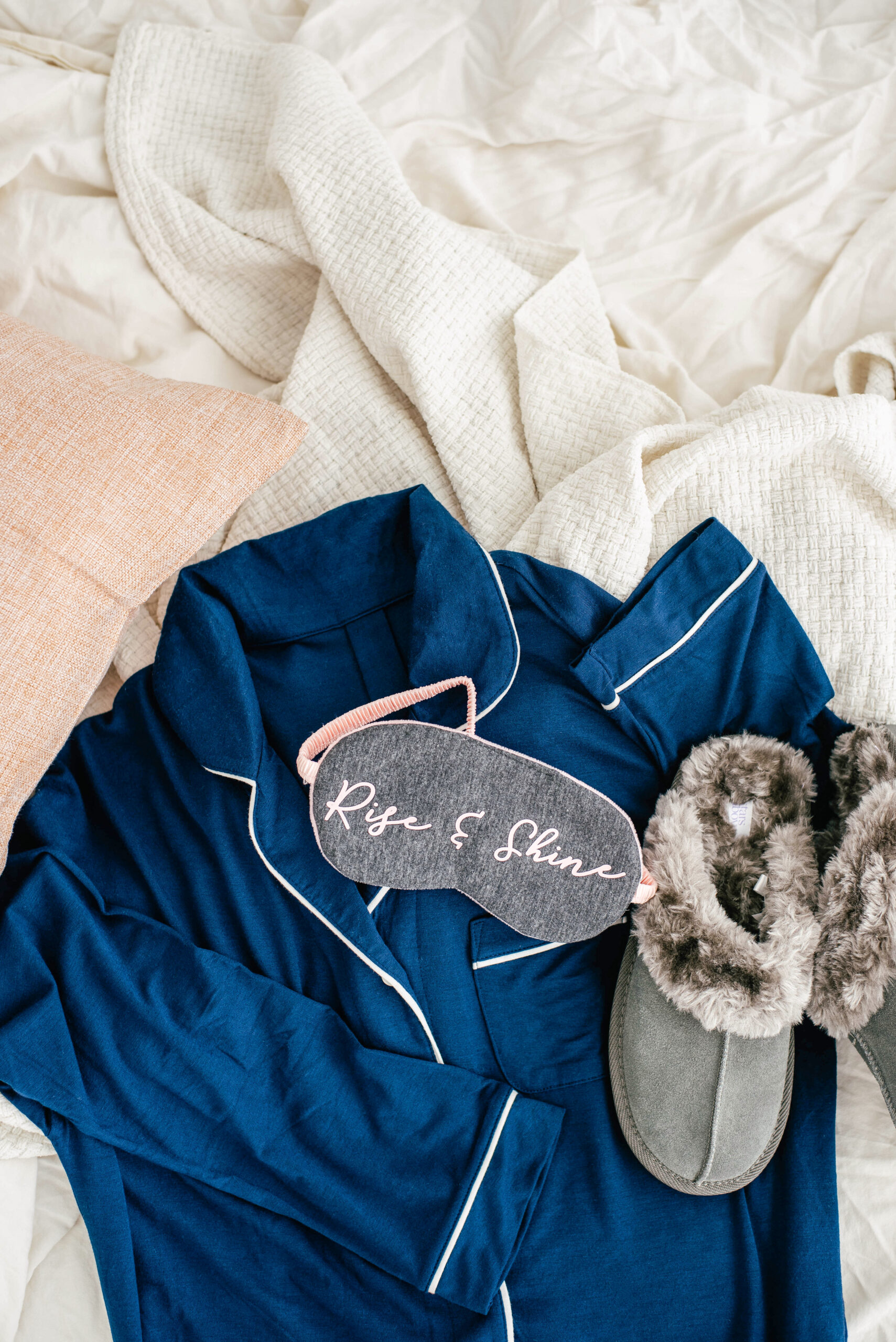 robe, slippers, and sleep mask on a messy bed