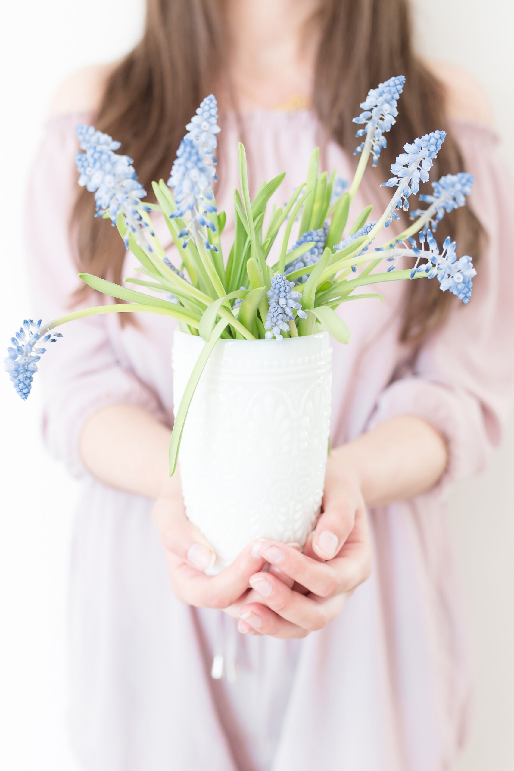 non descript woman holding out a vase of wildflowers