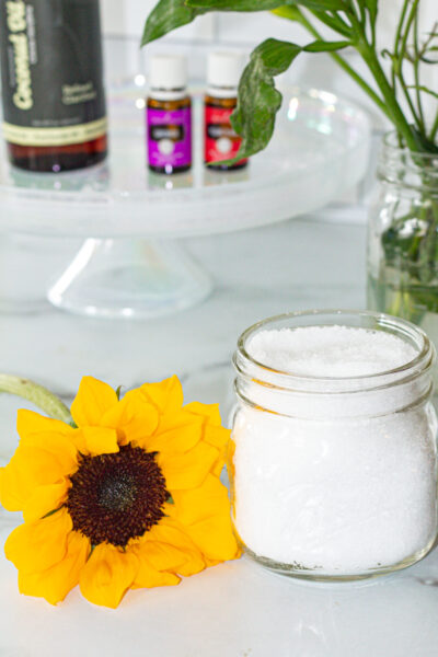 jar of bath salts, a sun flower, and bottles of essential oil