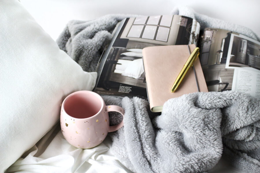 Hygge scene with books, fur blanket, fluffy pillow, and mug