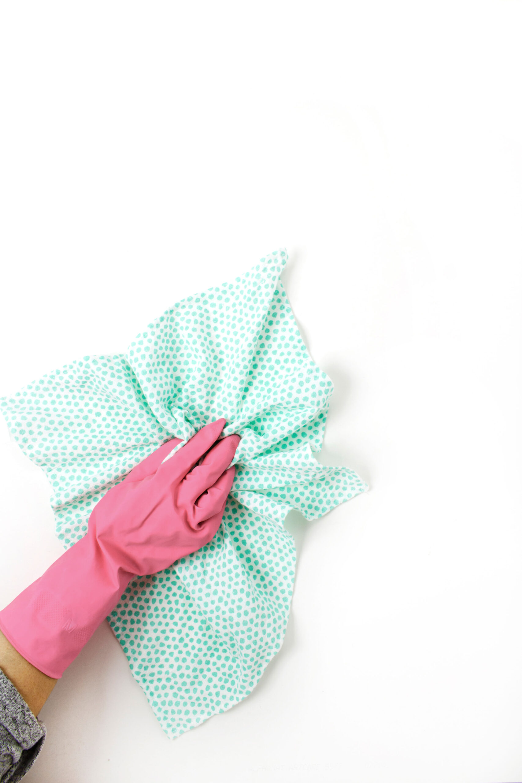 pink gloved hand holding a green and white cleaning cloth