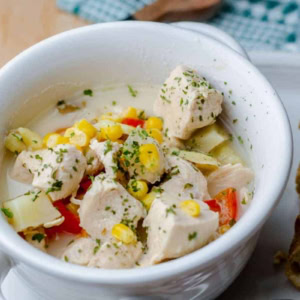 white bowl with Boma Chicken Corn Chowder and a slice of crusty bread