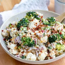 broccoli cauliflower salad with cheese and bacon in a white serving bowl
