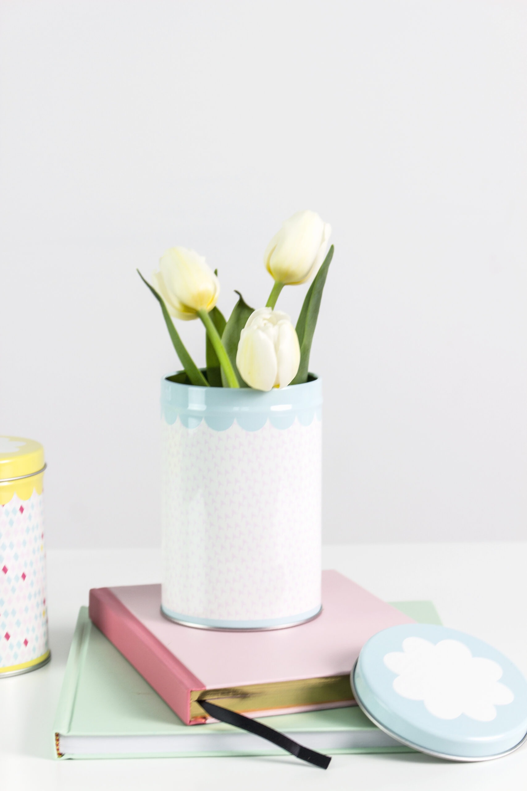 tin vase with yellow flowers on top of a pile of two books