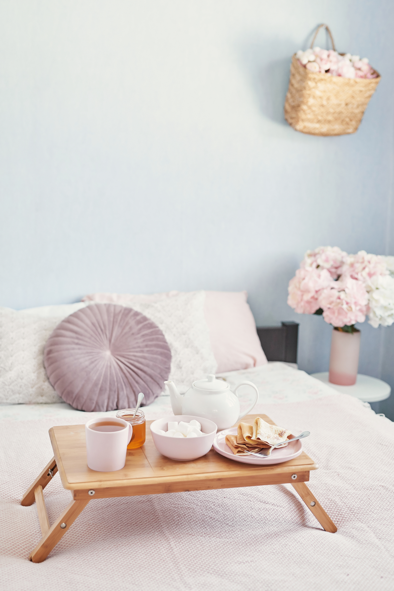 Breakfast in bed in hotel room.Accommodation. Breakfast in bed with tea cup with pancakes on tray on bed background top view. Copy Space. Romantic valentine's day breakfast. Cozy breakfast