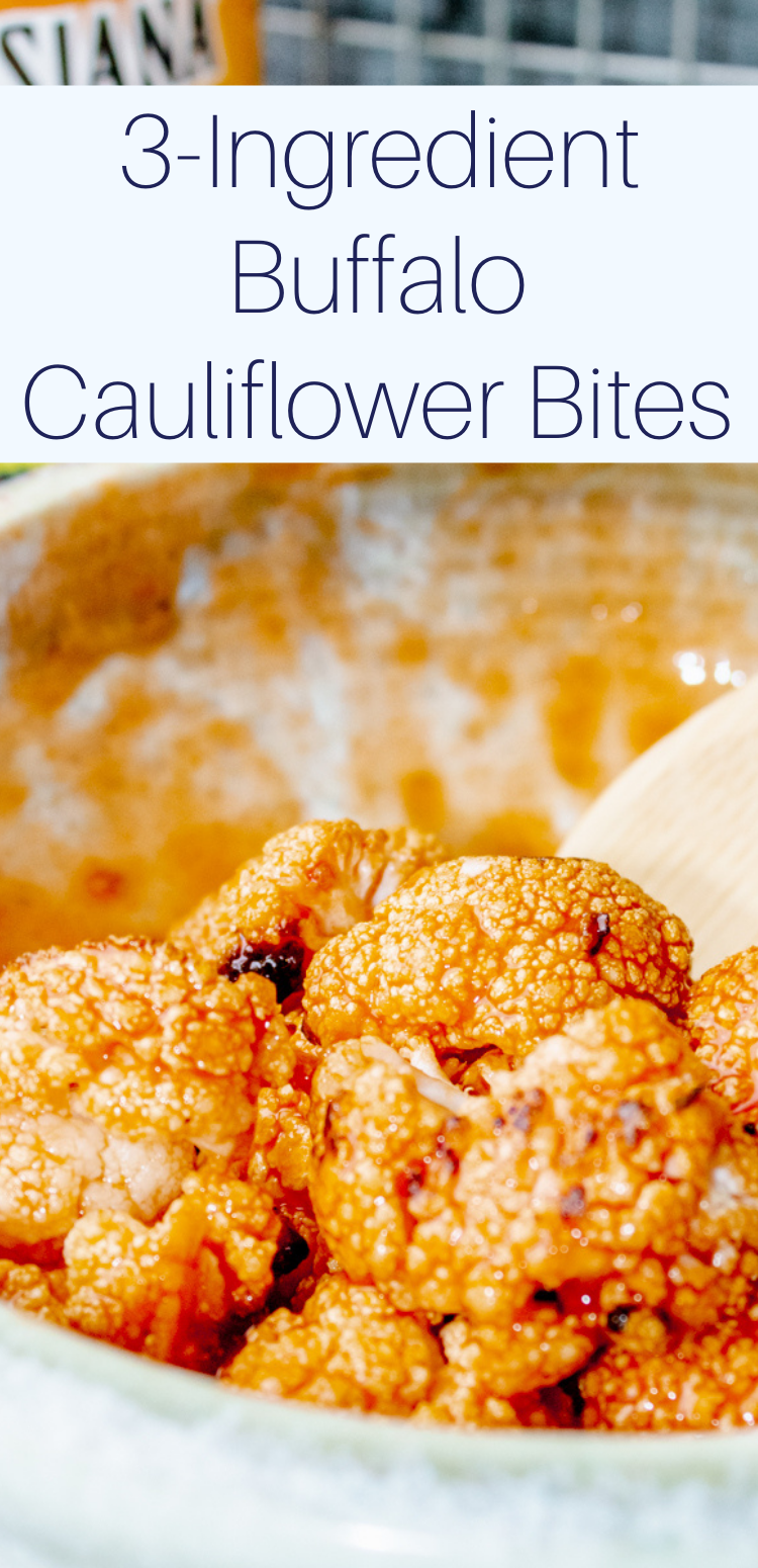 roasted buffalo cauliflower bites in a bowl with a wooden spoon and hot sauce in the background with text overlay "3-Ingredient Buffalo Cauliflower Bites"