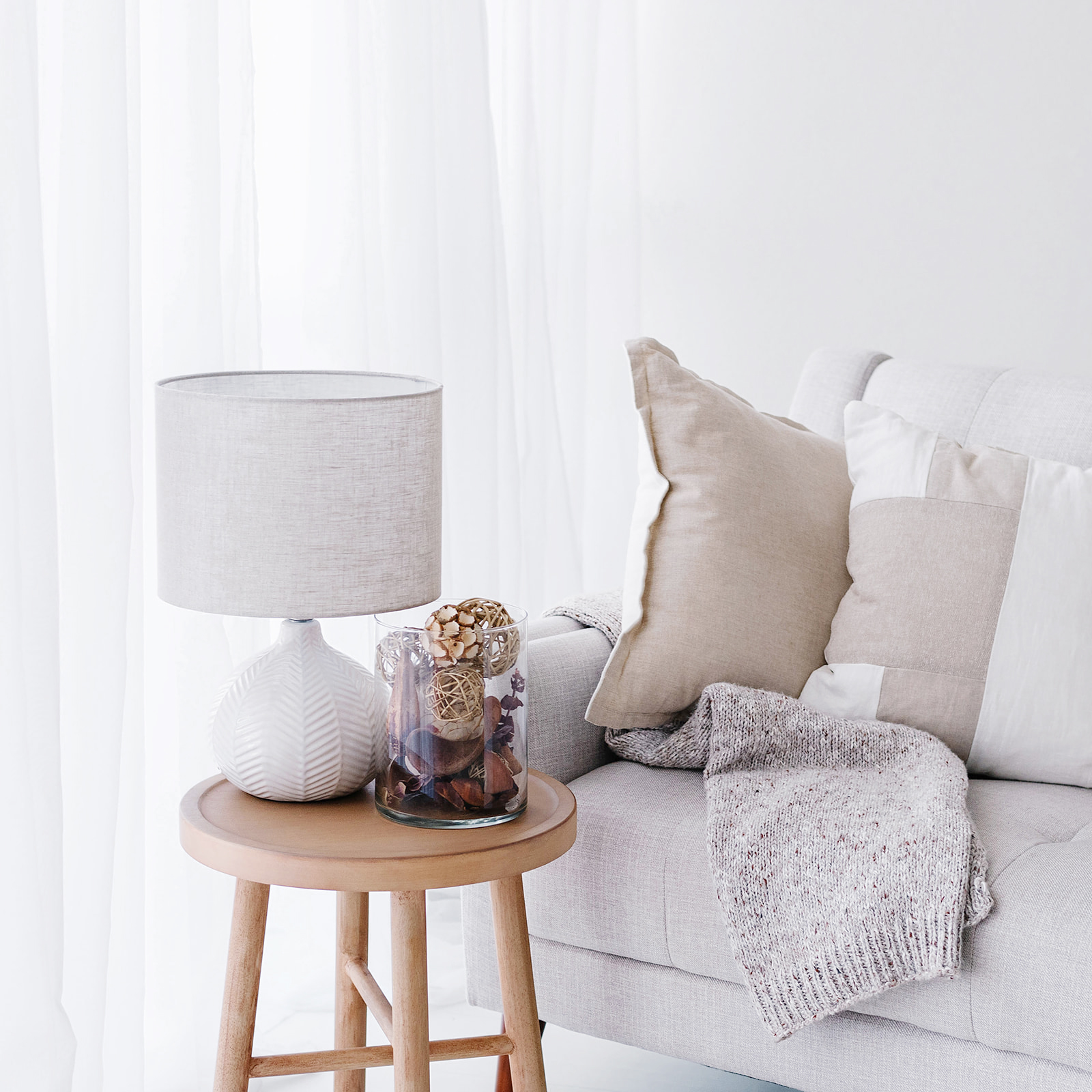 living room scene with throw pillows, blankets, a side table, lamp, and fall decor