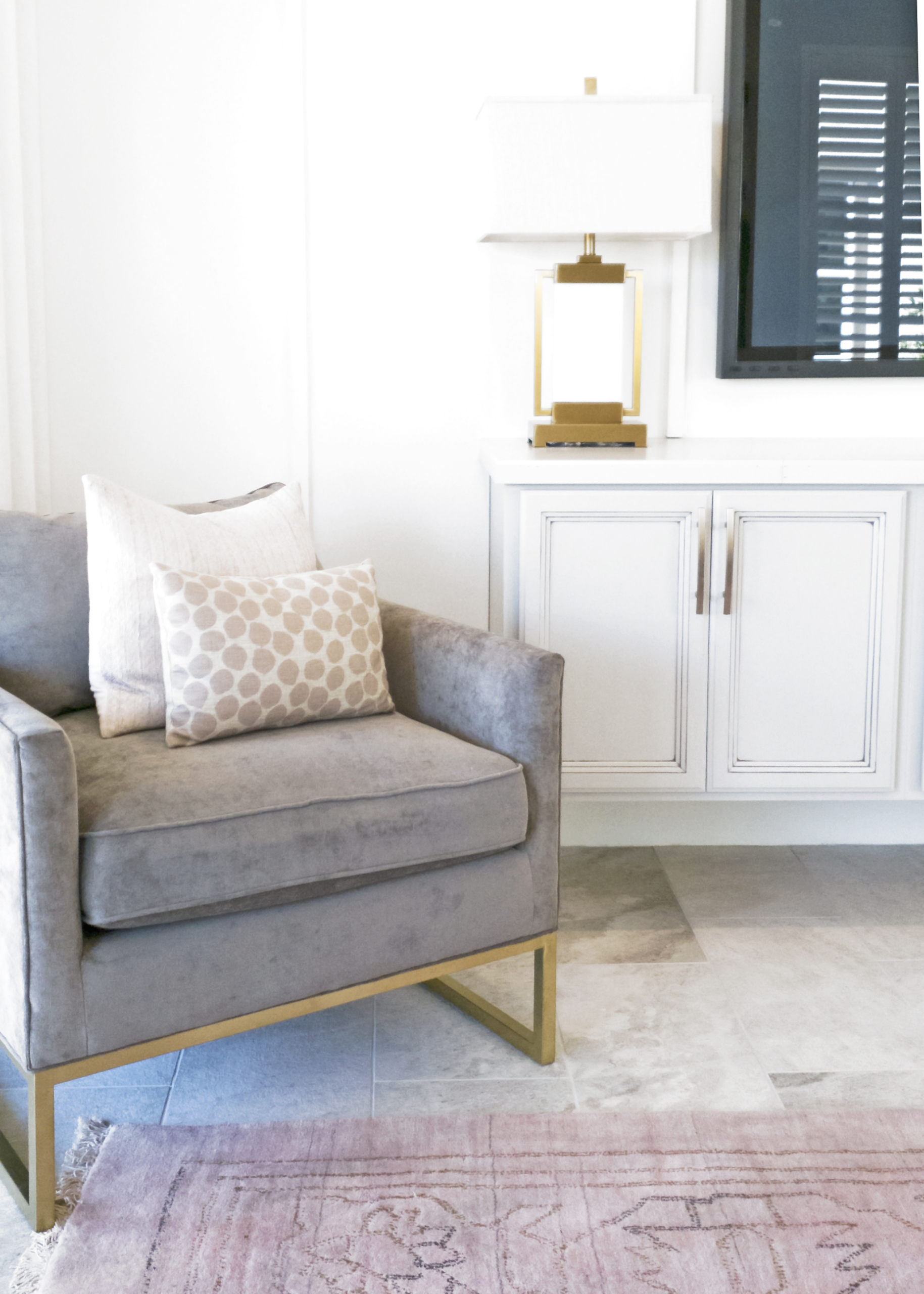 Living room scene with chair and pillows, lamp, and cabinet