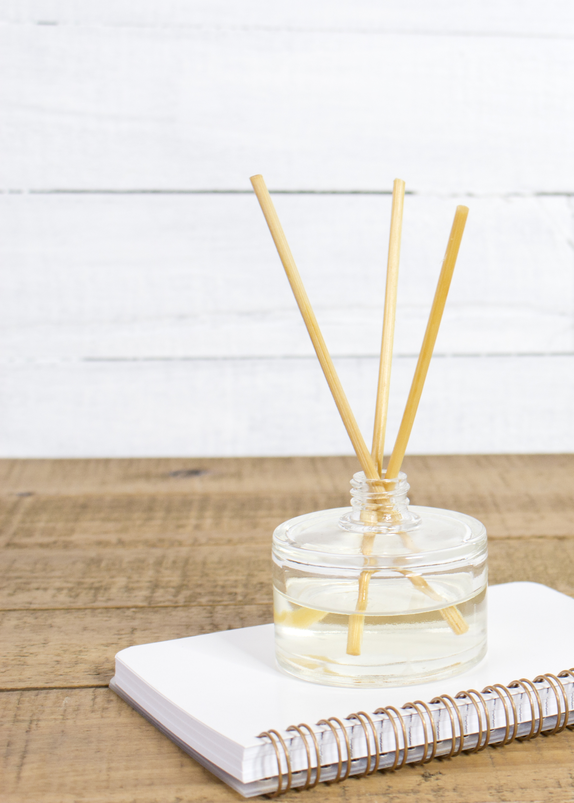 diffuser reeds in oil siting atop a spiral bound notebook