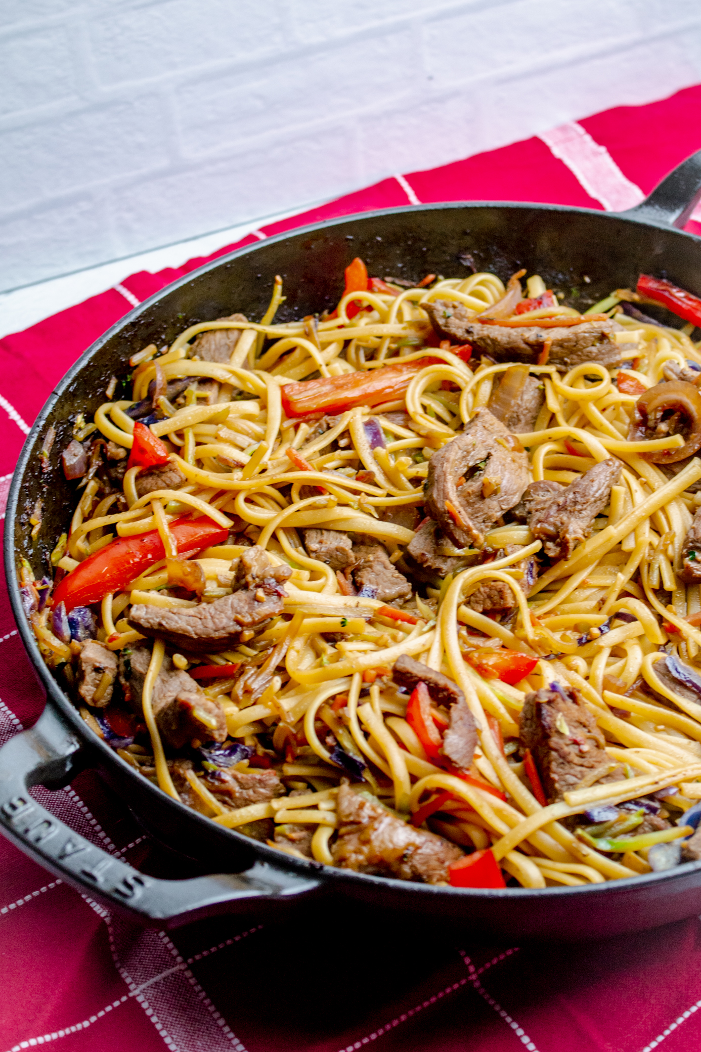 Close up of a Staub pan filled with Asian Beef and Noodles Stir Fry