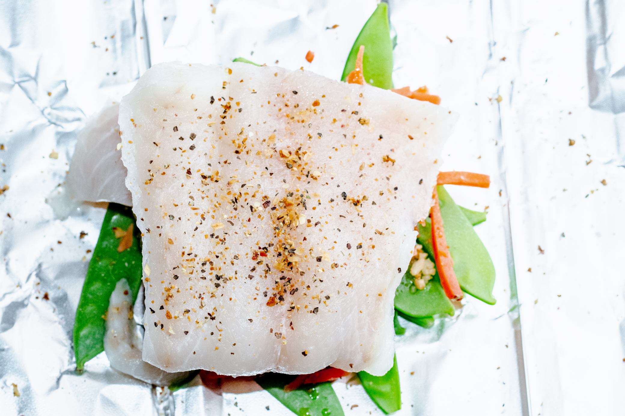 uncooled walleye fillet on top of a layer of veggies