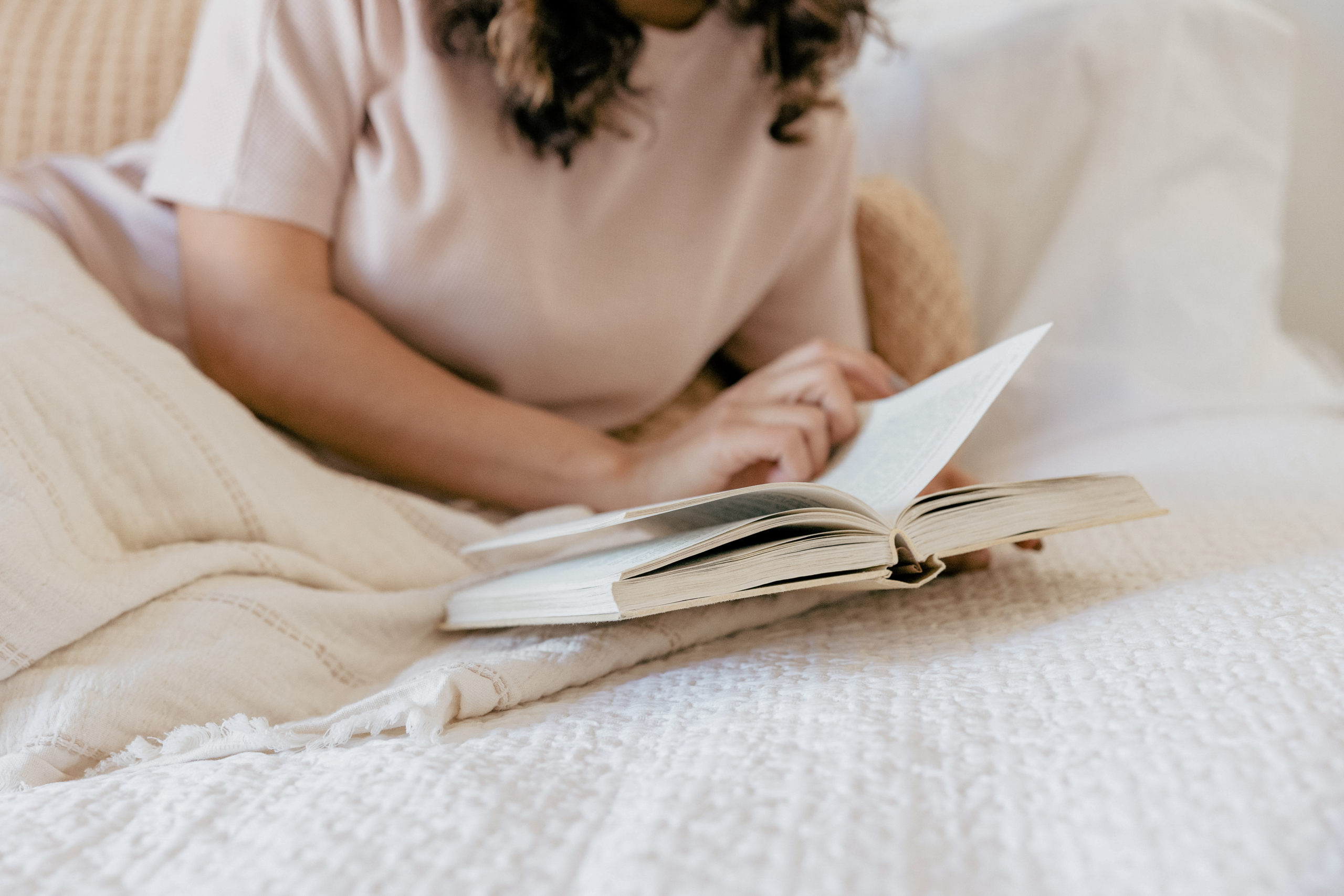 Non descript woman laying in bed reading a book