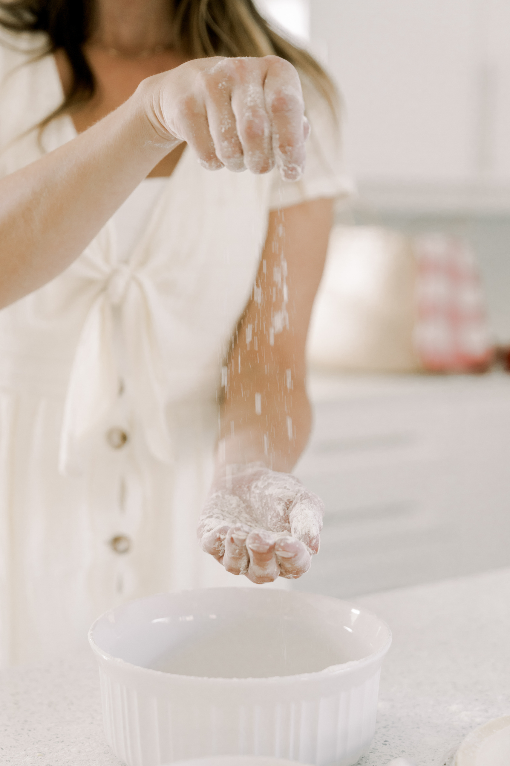 non descript woman in the kitchen sprinkling flour into her hand