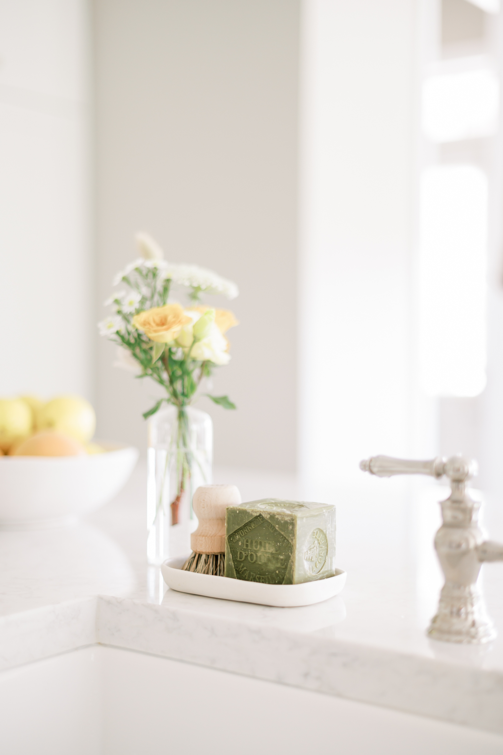 Flowers and scrubbing brush next to a kitchen sink