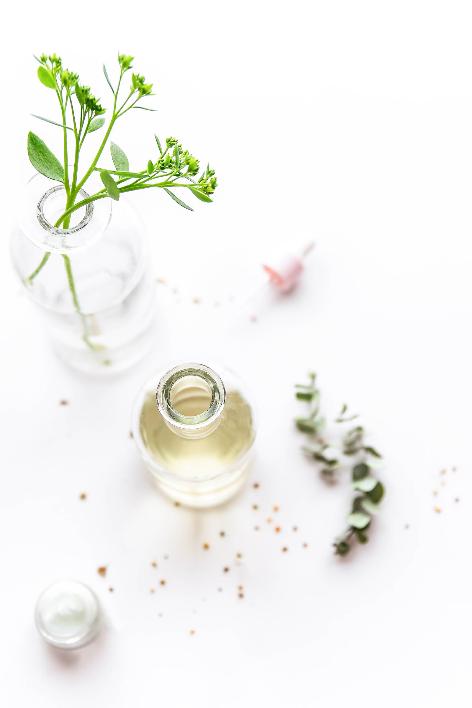 overhead view of an open bottle of essential oils and greenery in a vase of water