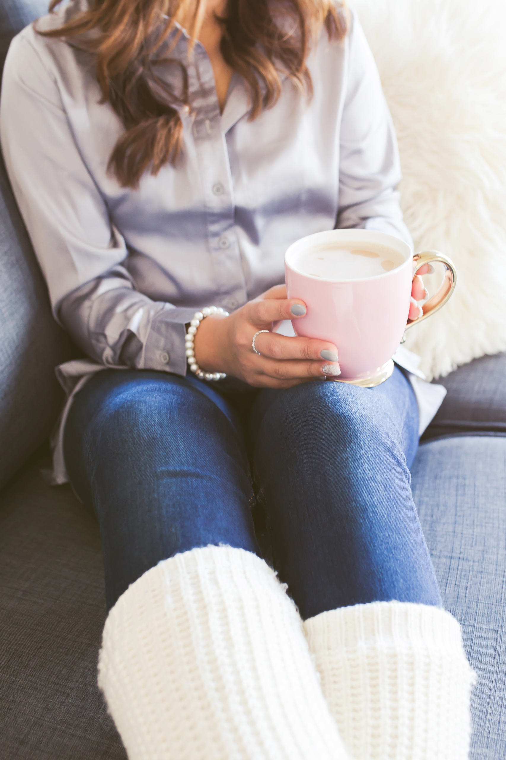 woman relaxing on a couch with a ping mug of coffee