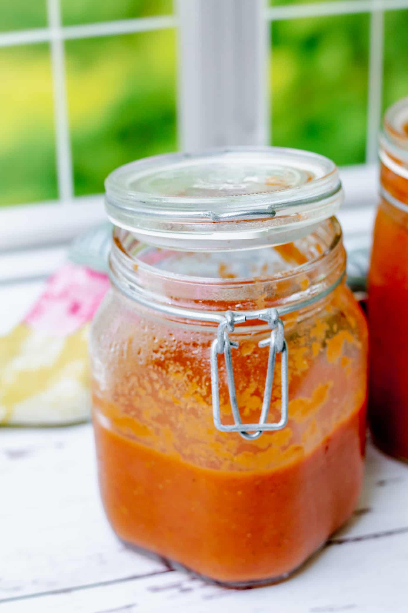 open jar of homemade tomato sauce in front of a window