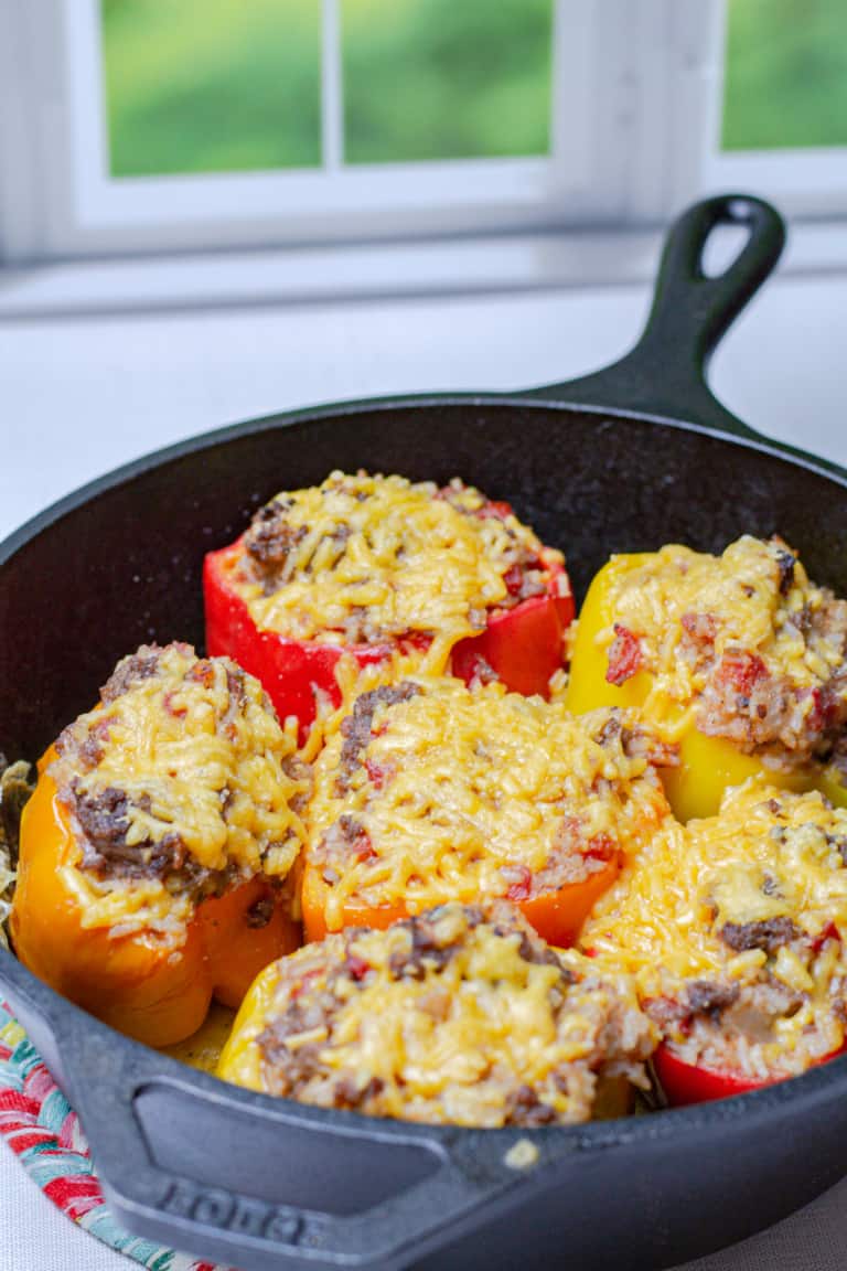 pan of 5 crisp beef stuffed peppers smothered in cheese with a window in the background