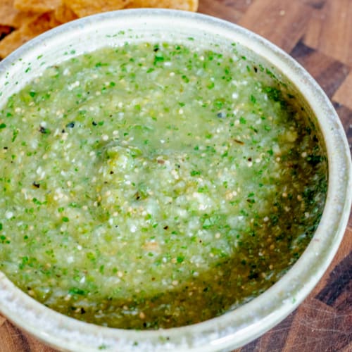 close up of a bowl of fresh salsa Verde on a wooden cutting board