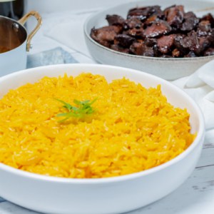 white bowl filled with yellow basmati mediterranean rice with dishes in the background