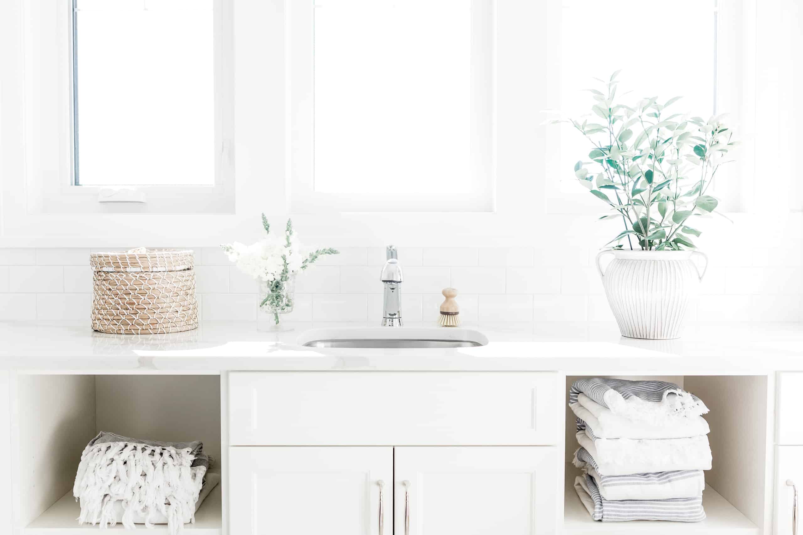 Bathroom counter with plant, a wicker basket, and cubbies of towels below