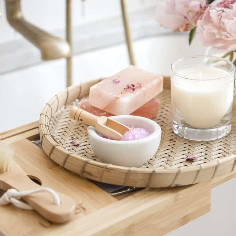 bathtub tray filled with spa products and a candle