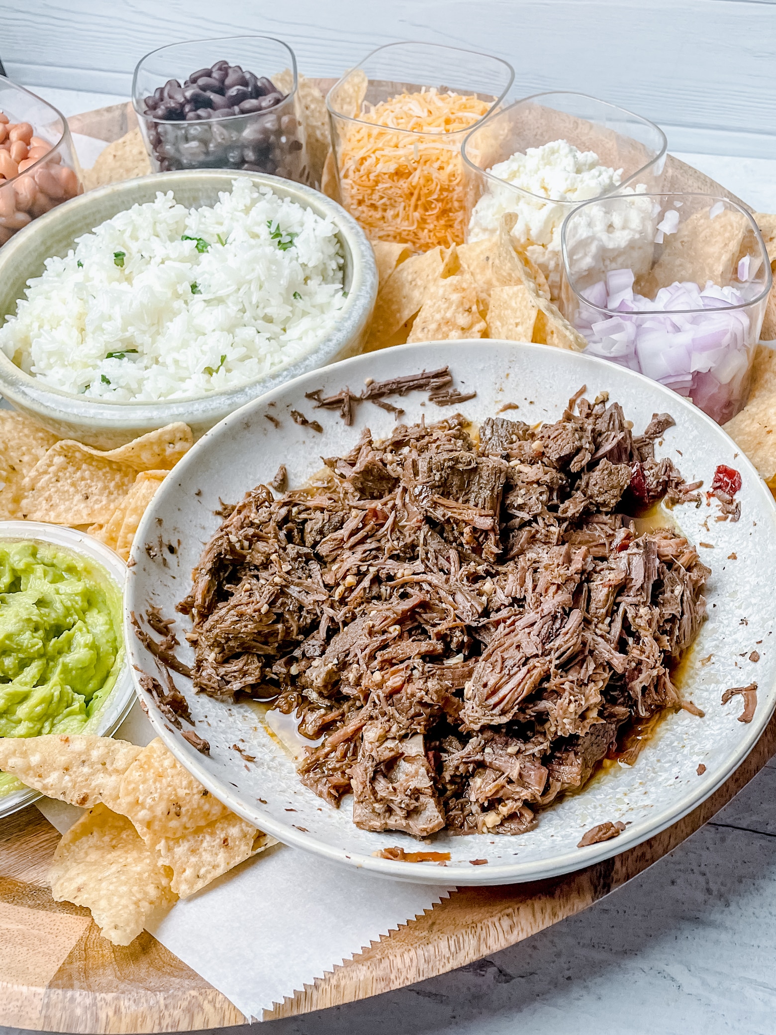 overhead view of a charcuterie board of beef barbacoa and toppings