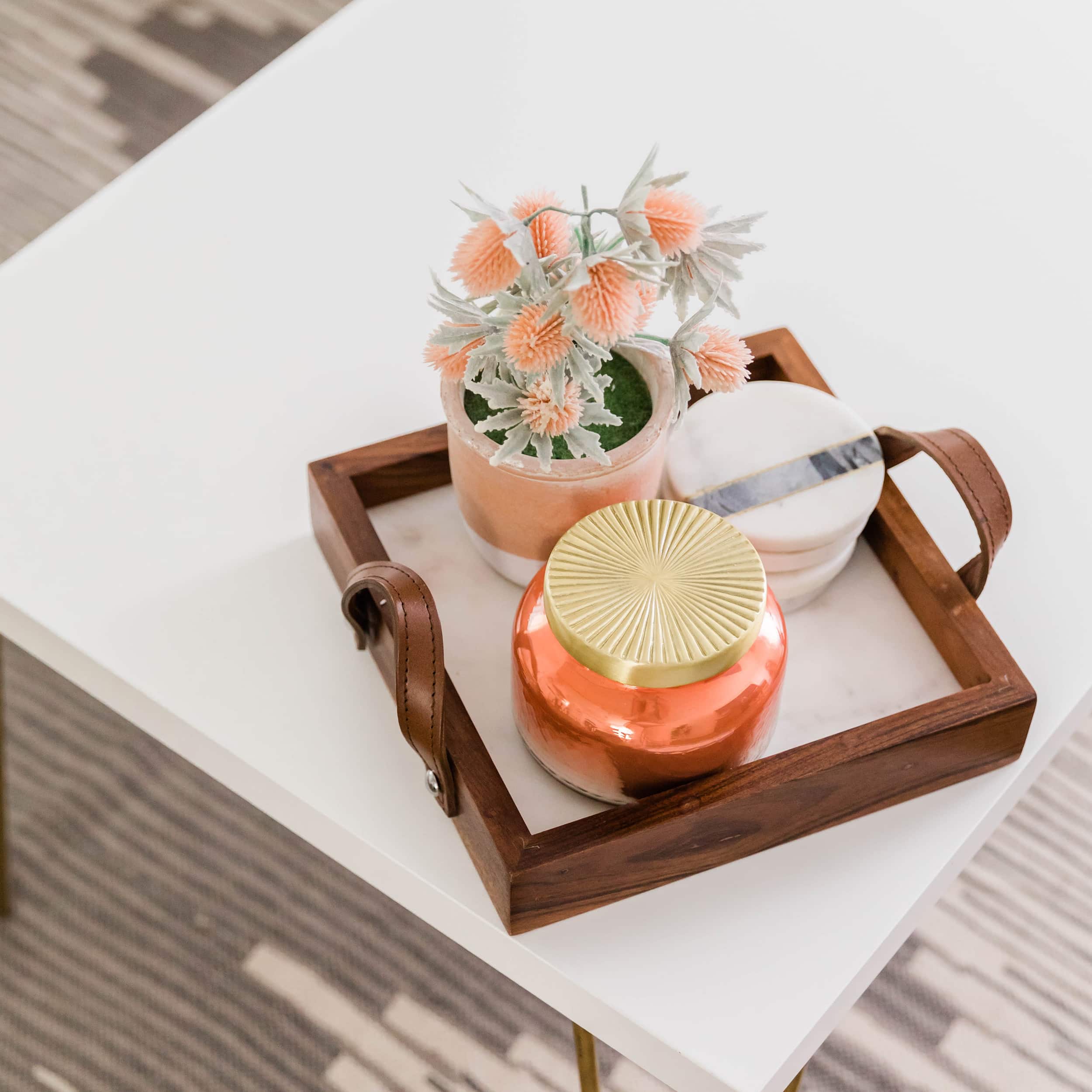 overhead view of small tray on a table that contains faux fall plant, candle, and coasters