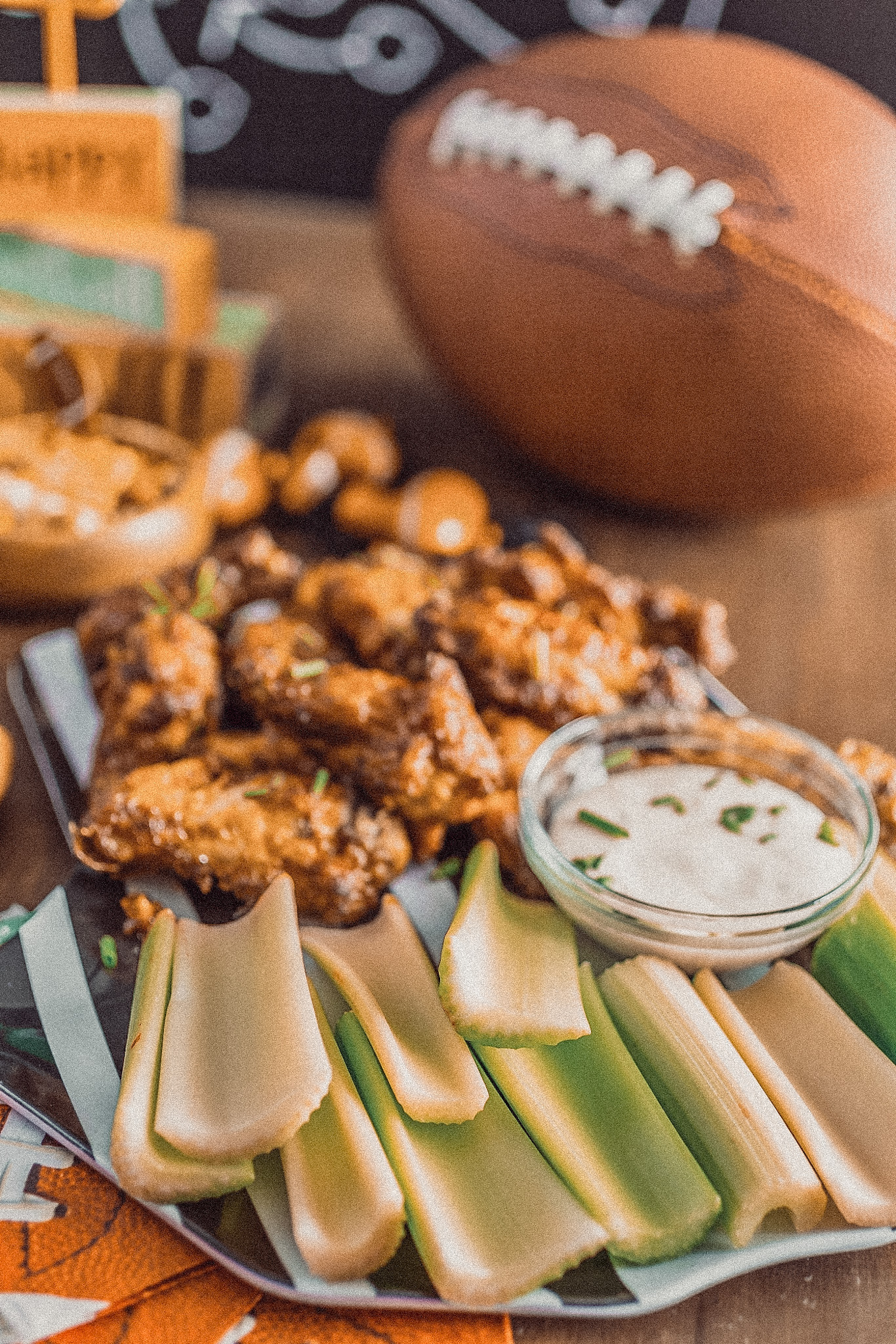 wings, celery, and ranch dip next to a football on a table