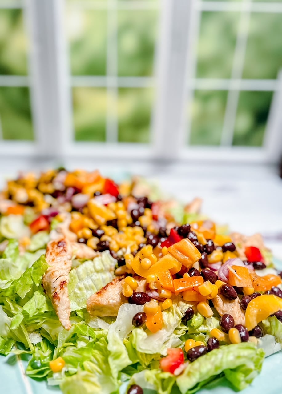 platter of cowboy caviar salad with chicken at an angle in front of a window