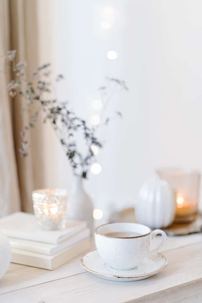 elegant scene with coffee cup, candles, flowers, and books