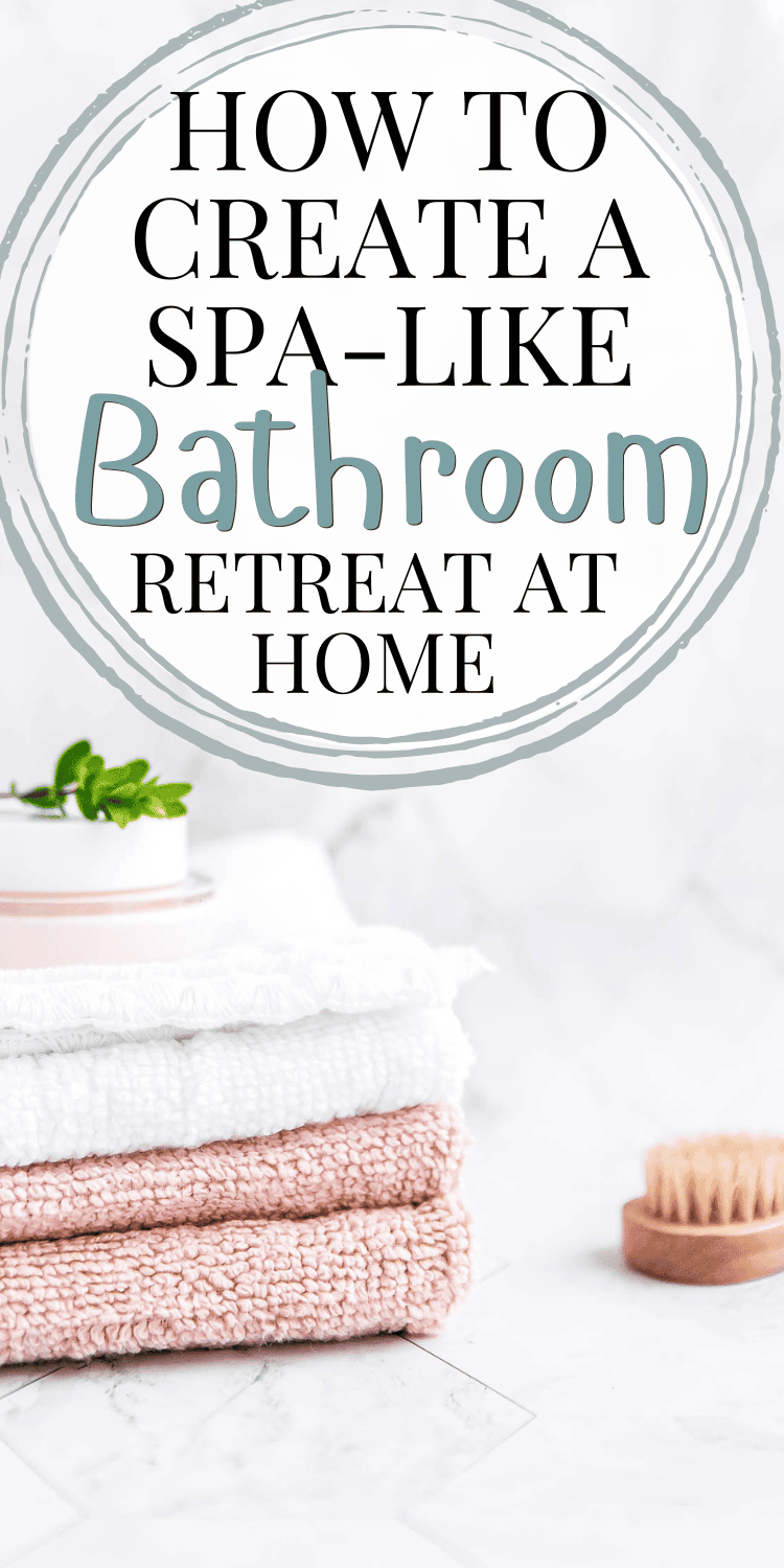 A serene and stylish image featuring a stack of white and blush pink towels with a small jar of cream on top, complemented by a wooden dry brush and greenery, against a marble background. The text overlay reads "How to Create a Spa-Like Bathroom Retreat at Home" in elegant fonts.