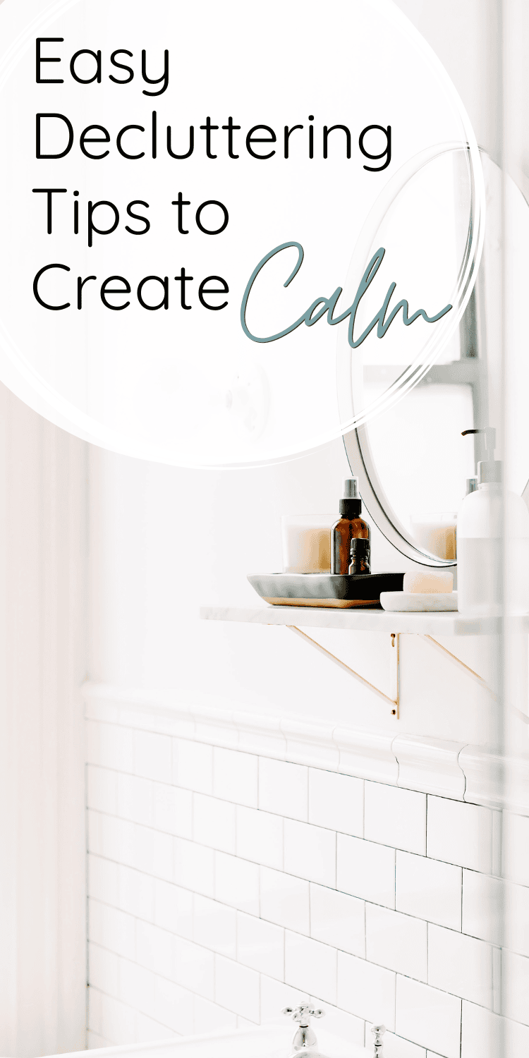 A Pinterest pin with a clean bathroom setup showcasing a round mirror, a marble shelf, and neatly arranged essentials like candles and bottles. Overlay text reads 'Easy Decluttering Tips to Create Calm.' The design exudes tranquility and minimalism.