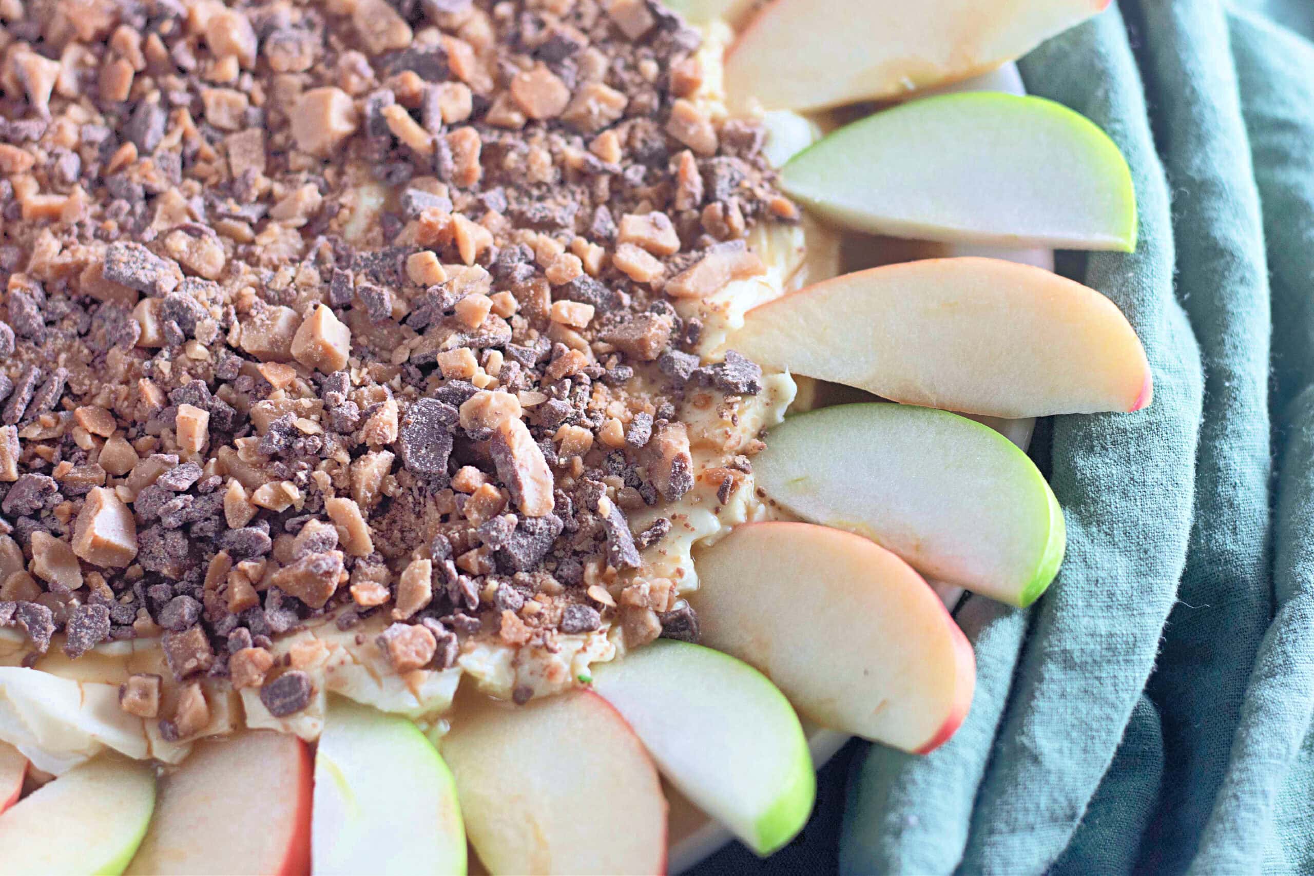 A full view of a toffee apple dip served on a round plate, beautifully garnished with neatly arranged red and green apple slices, ready for dipping.