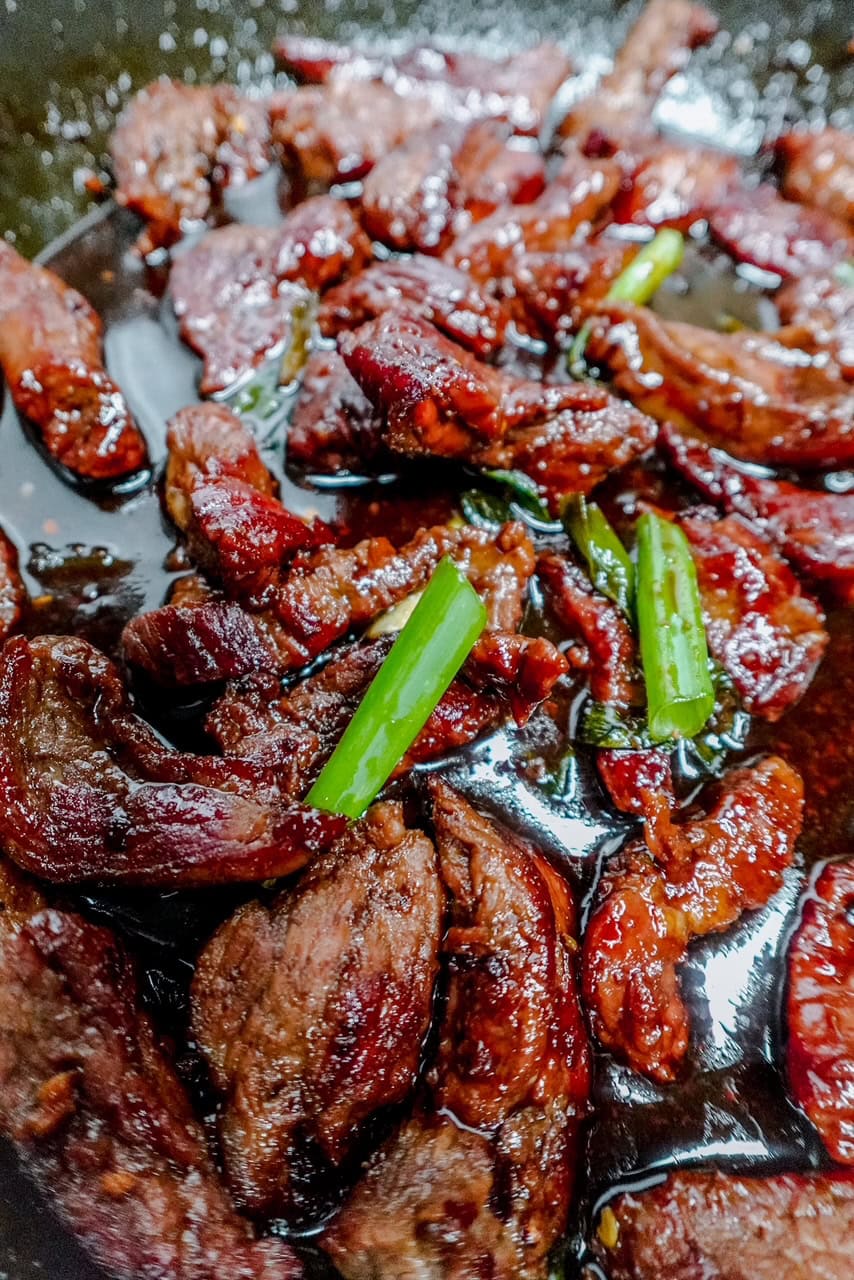 Macro shot of juicy keto Mongolian beef pieces coated in a glossy, savory sauce and garnished with green onions for a bold, low-carb dinner option.