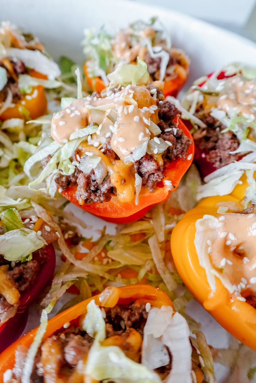 Extreme close-up of a single red bell pepper half, overflowing with seasoned beef, shredded lettuce, cheese, and creamy sauce, clearly showing texture and freshness.