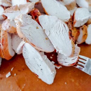 close up view of chopped cooked chicken with a fork sticking in one of the pieces.