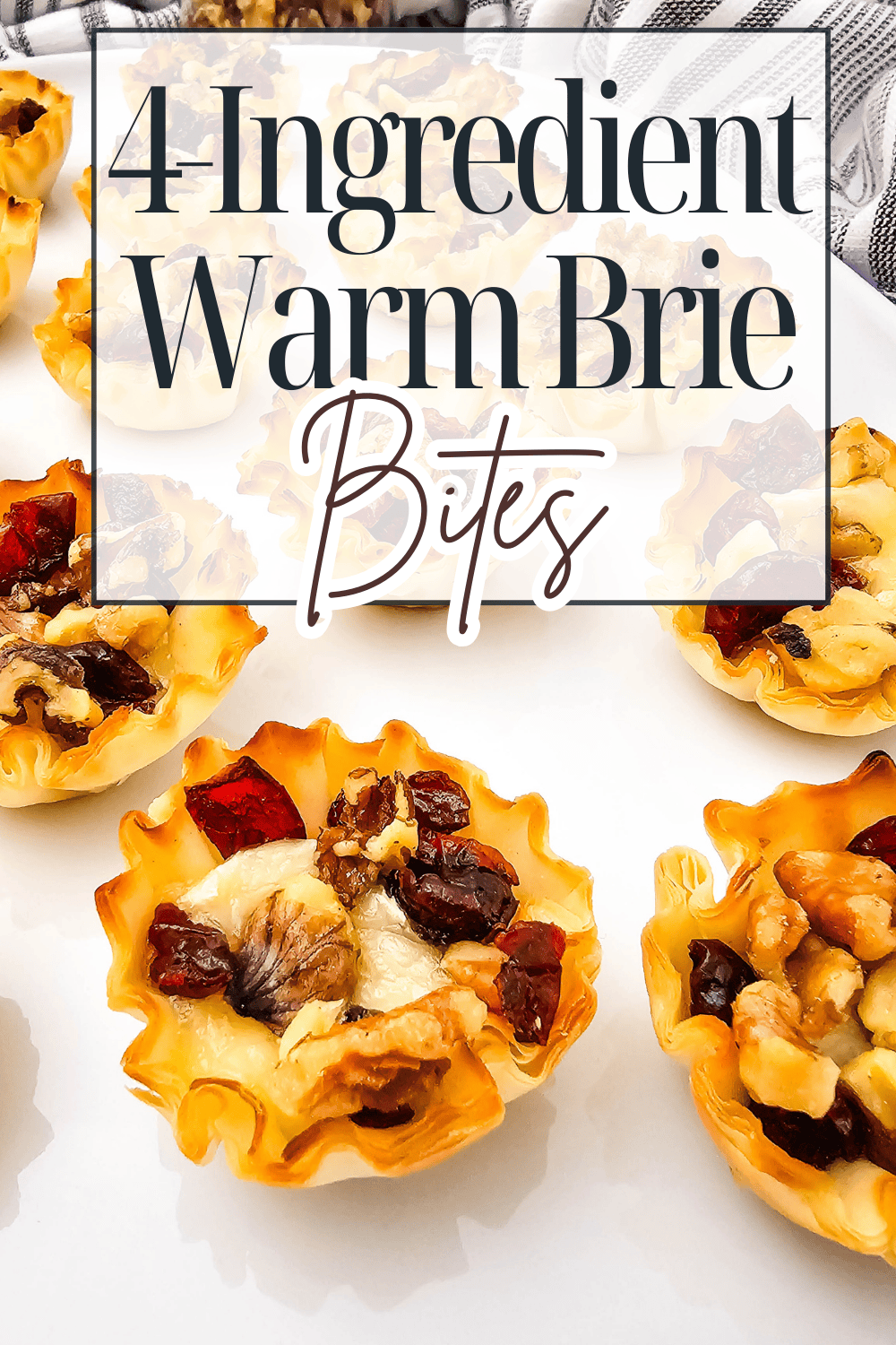 Mini phyllo cups filled with melted brie cheese, walnuts, and dried cranberries are arranged on a white surface. Text overlay reads: 4 Ingredient Warm Brie Bites.