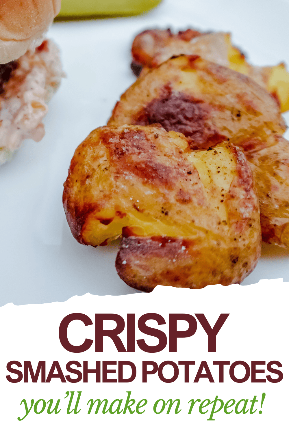 Golden-brown smashed potatoes on a white plate with part of a sandwich visible in the background. Text below reads: Crispy smashed potatoes youll make on repeat!.