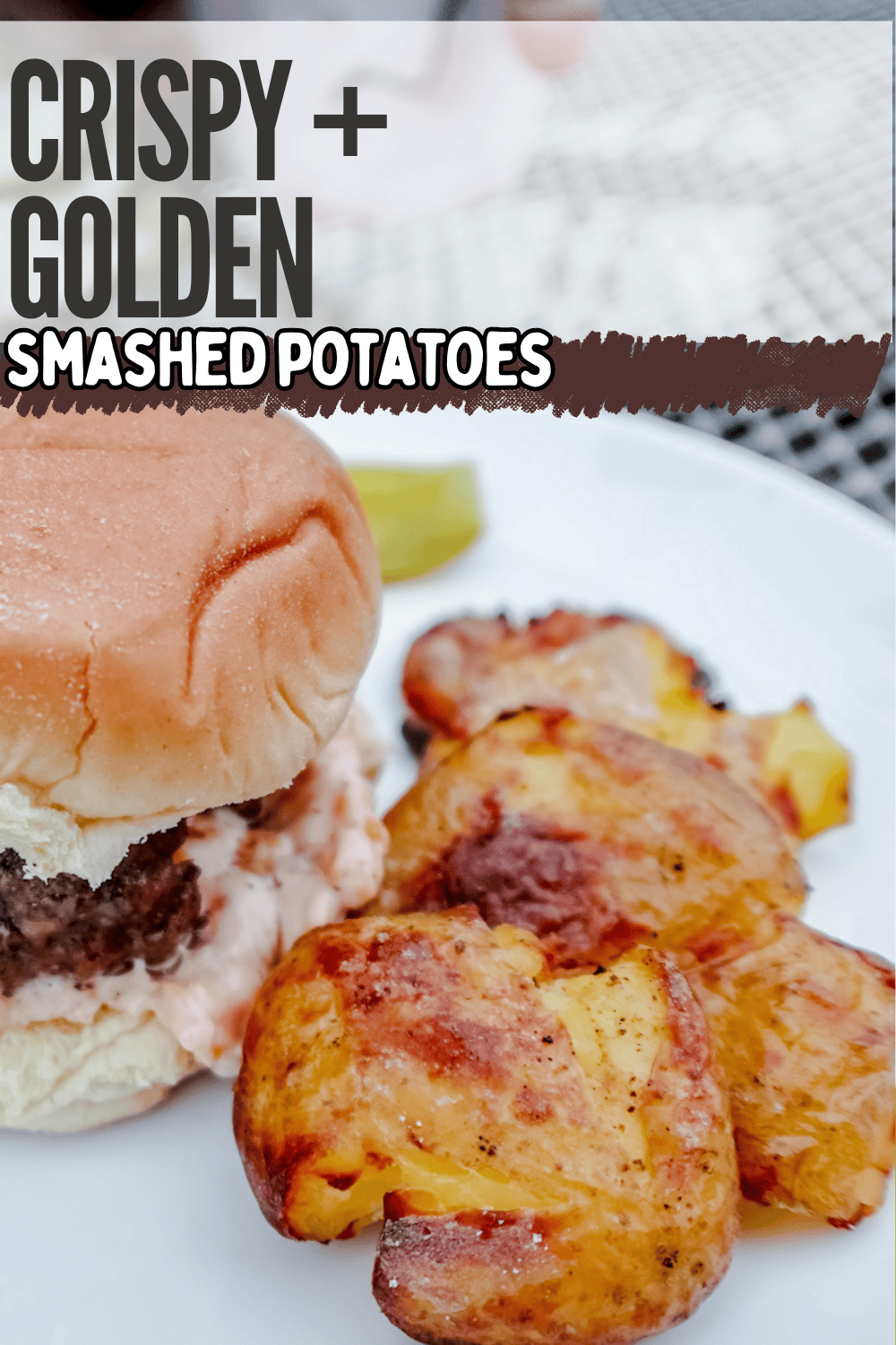 A close-up of a plate with a cheeseburger in a bun and golden, crispy smashed potatoes, accompanied by bold text reading “Crispy + Golden Smashed Potatoes.”.