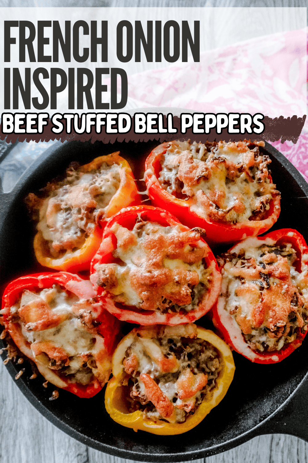 A skillet filled with red and yellow bell peppers stuffed with a beef mixture and topped with melted cheese. The text reads, French Onion Inspired Beef Stuffed Bell Peppers.