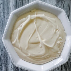 Overhead shot of a white octagonal bowl filled with smooth Bavarian cream sits on a gray wooden surface.